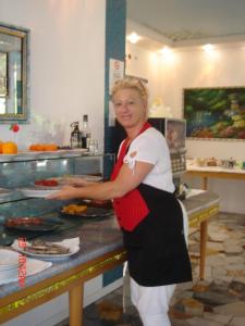 a woman standing in a kitchen preparing food at Hotel Da Giovanna in Lignano Sabbiadoro