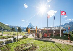 a train station with the canadian flag and mountains at Riffelalp Resort 2222m in Zermatt