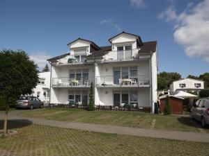 ein großes weißes Haus mit einem Zaun davor in der Unterkunft Appartementhaus Anne in Binz