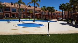una gran piscina en un patio con palmeras y un edificio en Villa Jardins 2 by Sunny Deluxe, en Albufeira