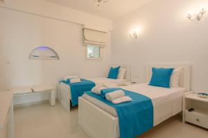 2 Betten in einem weißen Zimmer mit blauen Akzenten in der Unterkunft Aristodimos Luxury Apartments in Kalamaki