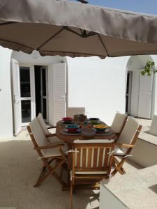 a table with chairs and an umbrella on a patio at Dammuso SOLMAR in Pantelleria