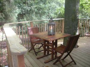 a wooden table with two chairs and a lantern on a deck at B&B La Cabane du Bois Dormant in Spa