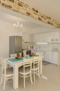 una cocina blanca con mesa y sillas. en Aristodimos Luxury Apartments, en Kalamaki