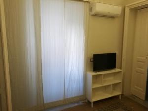 una tv seduta su uno scaffale accanto a una tenda di Ursino rooms apartment a Catania