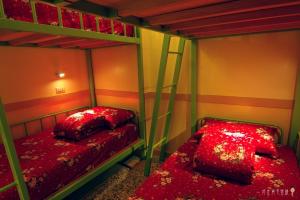 two bunk beds in a room with red sheets at Beigang Nice Stay in Beigang