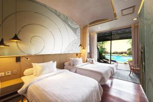 three beds in a room with a view of a pool at Sawasdee Village in Kata Beach