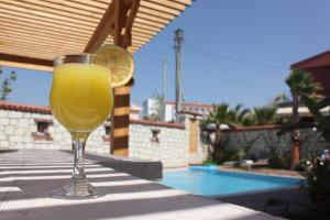 a glass of orange juice sitting on a table next to a pool at Eritrina Alacati in Alacati