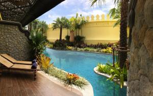 a swimming pool in a resort with a bench and palm trees at Sawasdee Village in Kata Beach