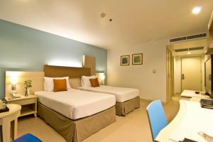 a hotel room with two beds and a television at Sunshine Vista Hotel - SHA Plus in Pattaya