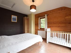 Verpré的住宿－Duplex Chalet in Rendeux Ardennes with Sauna and Terrace，卧室配有白色的床和婴儿床。