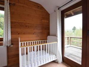 una culla in una stanza con parete in legno di Duplex Chalet in Rendeux Ardennes with Sauna and Terrace a Verpré