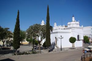 a white church with trees in front of it at CASA PERIN - HOSTAL RURAL in Villafranca de los Barros