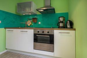 una cucina con mobili bianchi e una stufa di Ferienwohnungen Proll a Bansin