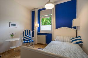 Schlafzimmer mit blauen Wänden, einem Bett und einem Stuhl in der Unterkunft Ferienwohnungen Proll in Bansin