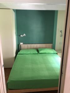 a bed with a green comforter in a room at Ort holiday's time in Orco Feglino