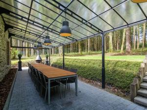 un patio con mesa y sillas bajo un techo de cristal en Luxury home in Gedinne with bubble bath and sauna en Gedinne