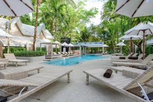 a swimming pool with lounge chairs and umbrellas at Deevana Krabi Resort in Ao Nang Beach