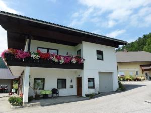 a white house with flowers on a balcony at Ferienwohnung Gimplbauer in Faistenau