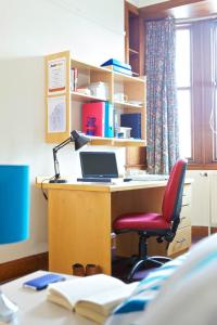 an office with a desk with a laptop and a red chair at McIntosh Hall Campus Accommodation in St. Andrews