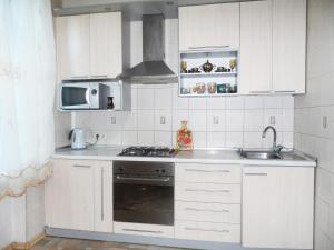 Il comprend une cuisine blanche équipée d'une cuisinière et d'un four micro-ondes. dans l'établissement Apartment on Skorykovskyi Lane 4, à Dnipro