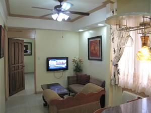 uma sala de estar com um sofá e uma televisão em Makati Suites at Travelers Inn em Manila