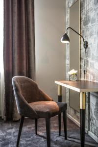 a chair sitting next to a desk with a lamp at Hotell Boras, BW Signature Collection in Borås