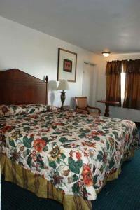 a bedroom with a bed with a floral bedspread at HWY Express Inn and Suites in Thatcher