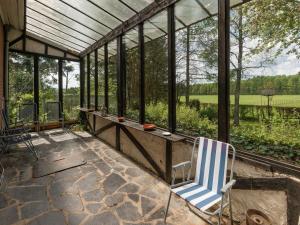 un salón acristalado con una silla azul y blanca en un patio en Holiday Home in Waimes with Private Garden, en Waimes