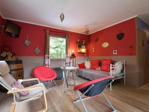 a living room with red walls and a couch and chairs at Chalet in a green and peaceful environment in Houffalize