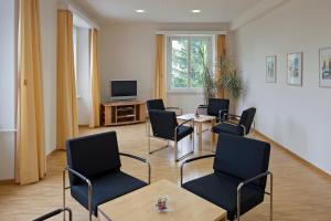 a waiting room with chairs and a table and a tv at Hotel Haus Schönstatt contactless-Check-In in Brig