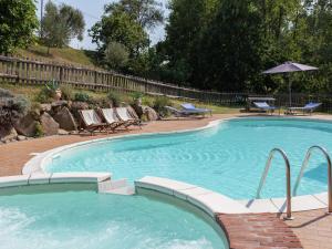 ein großer Pool mit Stühlen und einem Sonnenschirm in der Unterkunft Belvilla by OYO Agriturismo Valle Fiorita in Aulla