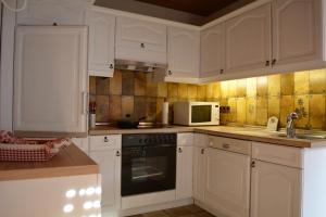 a kitchen with white cabinets and a microwave at Kleine Stuga in Windfuß