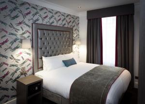 1 dormitorio con 1 cama grande y papel pintado con motivos florales en The Eaton Townhouse, en Londres