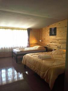 two beds in a room with wooden walls and a window at OYO 75472 GOTUM Hostel 2 & Money Exchange in Phuket
