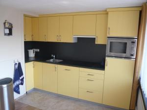 a kitchen with yellow cabinets and a microwave at Welca in Baarlo
