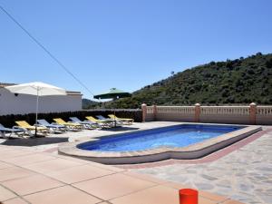 a swimming pool with lounge chairs and an umbrella at Belvilla by OYO Villa Alejandro in Sayalonga