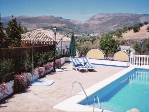 a swimming pool with two lounge chairs and an umbrella at Belvilla by OYO Casa Mi Pepe in Priego de Córdoba