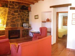 a living room with a stone fireplace and red chairs at Rural Farmhouse in Valencia de Alc ntara with Pool in La Borrega