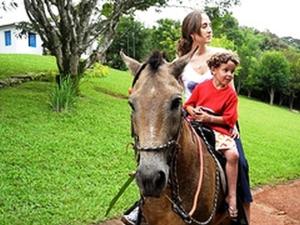 a woman and a child riding a horse at Hotel Fazenda Caco de Cuia in Itabirito