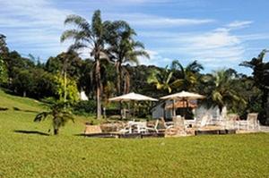 a resort with tables and umbrellas in a field at Hotel Fazenda Caco de Cuia in Itabirito