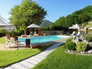 a swimming pool with chairs and umbrellas in a yard at Detached house in Cagli with swimming pool and garden in Acqualagna