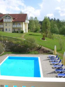 a swimming pool with lounge chairs and a house at Komforthotel Ahornhof in Lindberg