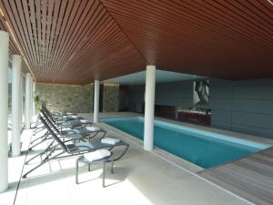 a swimming pool with lounge chairs next to a building at Holiday Home in Malmedy with Indoor Heated Pool in Malmedy