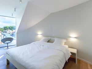 a bedroom with a white bed and a large window at Modern holiday home near Bruges and the North Sea in Dudzele
