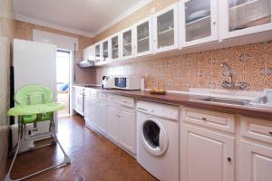 Una cocina con lavadora y una silla verde. en Em frente à Praia e Marina, en Vila do Conde