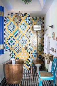 a bathroom with a tub and a tile wall at Salut Maroc! in Essaouira