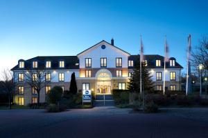 Best Western Hotel Helmstedt am Lappwald في هلمشتيت: مبنى ابيض كبير مع انارته