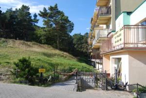 a building with a gate next to a hill at Apartament Na Wydmie - parter in Ustka