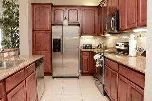 cocina con armarios de madera y nevera de acero inoxidable en Cayview Condo #231543, en Orlando